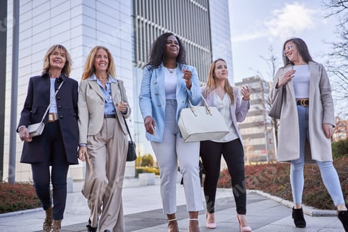 Preview: Businesswomen talking while walking together outdoors in financial district.