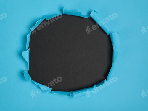 Preview: Center torn hole in blue paper revealing a black background. Space for text.black