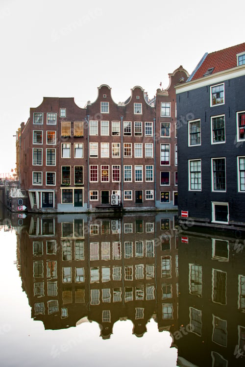 Vorschau: Amsterdamer Grachtenlandschaft mit traditionellen holländischen Häusern, die sich im Wasser spiegeln