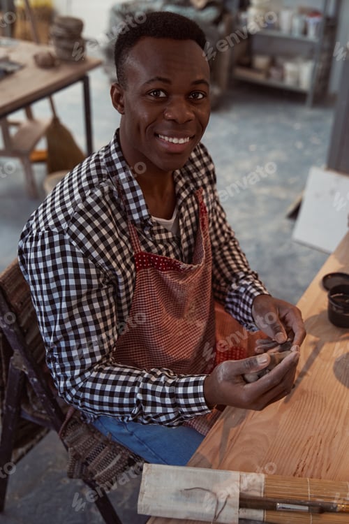 Preview: Joyous young male potter working with clay