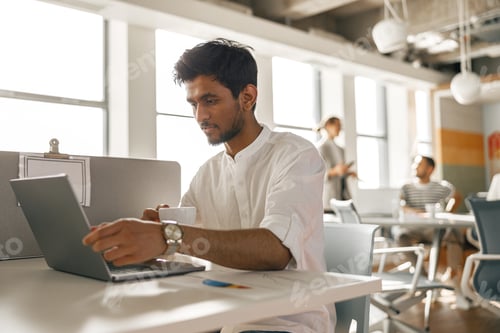 Preview: Businessman working laptop while sitting in modern office on colleagues background