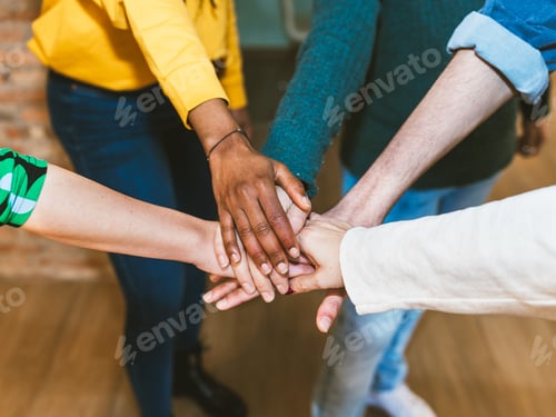 Preview: Hands of diverse young coworkers stacked in team unity