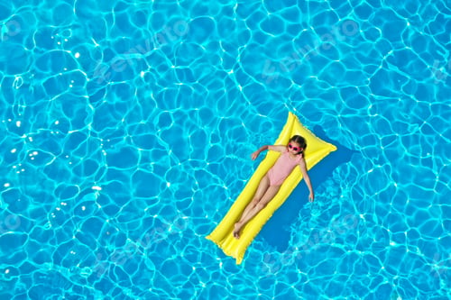Preview: Girl on inflatable mattress in swimming pool, top view. Summer vacation
