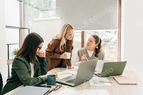 Preview: Business colleagues discussing over computer at desk in office