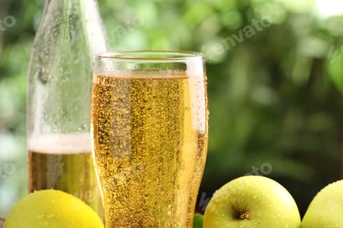 Preview: Delicious cider in glass, bottle and apples on blurred background, closeup