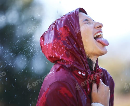 Preview: Carefree in the rain. Shot of a young woman sticking out her tongue to feel the rain outside.