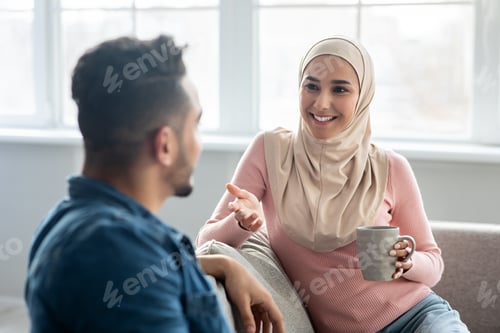 Preview: Cheerful lady in hijab having conversation with her husband