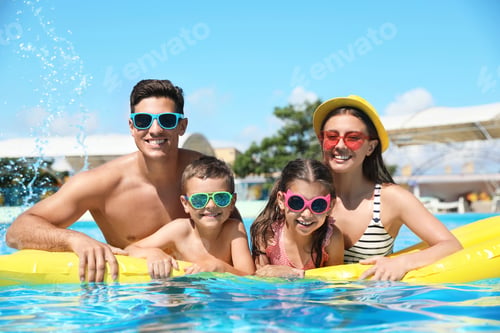 Preview: Happy family with inflatable mattress in swimming pool. Summer vacation