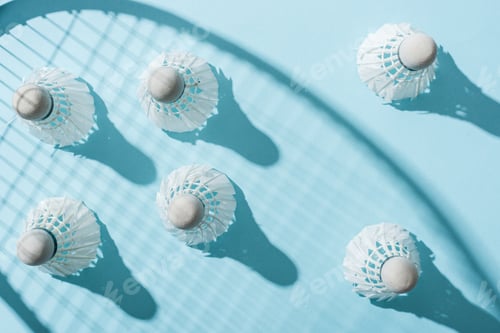 Preview: top view of shuttlecocks with feathers near shadow of badminton racket on blue