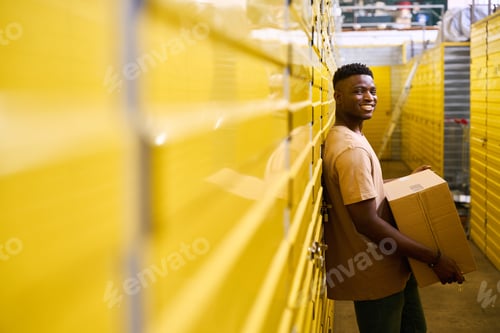 Preview: Curly-haired guy in jeans stands with a cardboard box