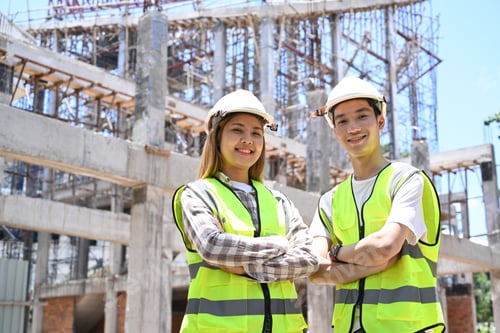 Preview: Architect and construction engineer wearing safety helmet standing with arms crossed.