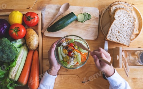 Preview: Top view image of a female chef cooking fresh mixed vegetables salad in kitchen
