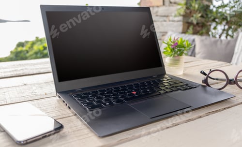 Preview: Blank screen laptop on the garden table, green nature background