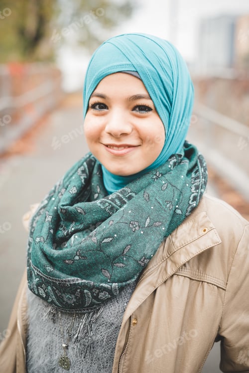 Preview: Portrait of young woman wearing turquoise hijab on park path