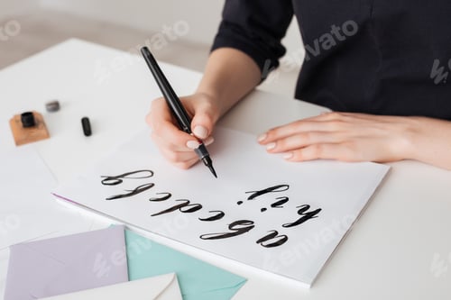 Preview: Portrait of young woman hands writing alphabet on paper on desk isolated