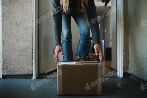 Preview: Woman getting her package from the front door during the coronavirus pandemic
