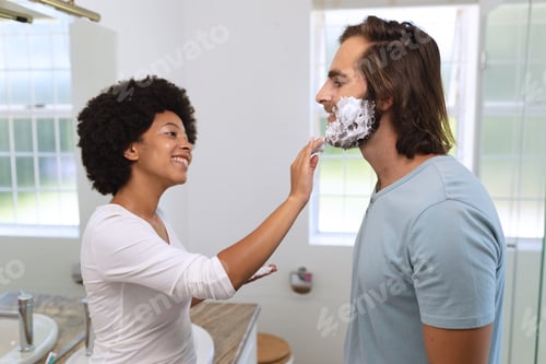 Preview: Diverse couple standing in bathroom applying shaving cream