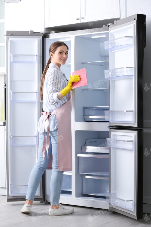 Preview: Woman in rubber gloves cleaning refrigerator at home
