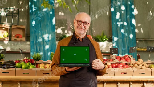 Preview: Elderly local farmer holding laptop with isolated greenscreen outdoors