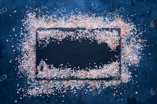 Preview: Himalayan rock salt on a slate board on dark blue background. Food background. Top view, copy space