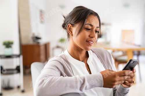 Preview: African mid woman using smartphone at home