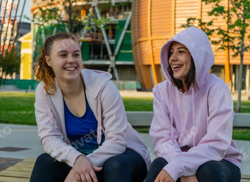 Preview: Caucasian girls sitting on stone talking and happily smiling - the concept of friendship