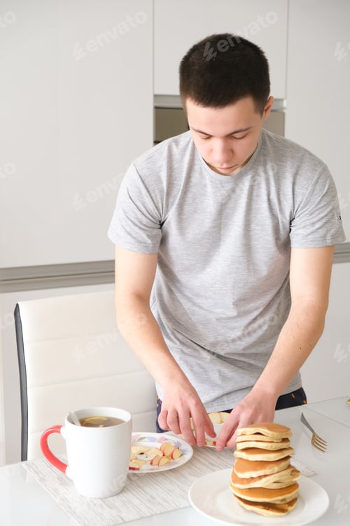 Preview: young guy preparing pancakes for breakfast