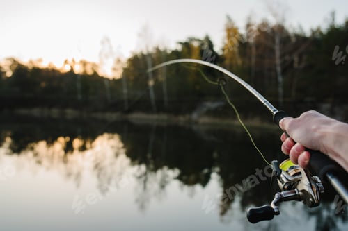 Preview: Fisherman with rod, spinning reel on the river bank. Sunrise. Fishing for pike, perch, carp. Fog