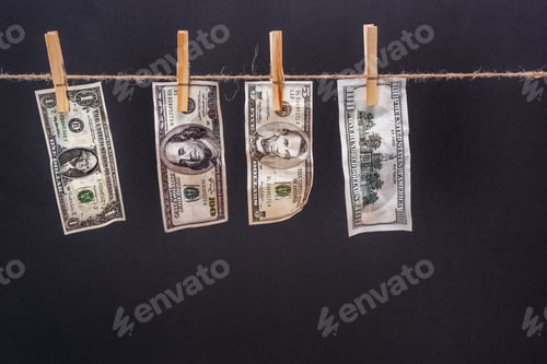 Preview: Close-up view of dollar banknotes hanging on rope isolated on black