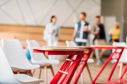 Preview: close-up shot of desks at classroom with blurred group of students on background