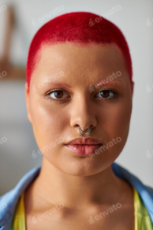 Preview: Vibrant young woman with bright red hair showcases unique style at home in the evening light