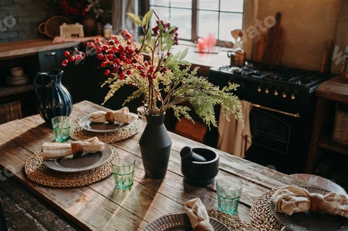 Preview: Served nicely decorated dining table with plates napkins vase. Kitchen background interior