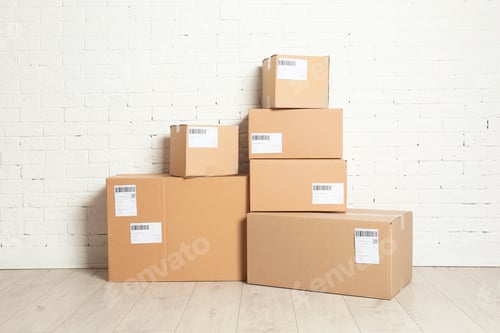 Preview: Stack of parcel boxes on floor against brick wall