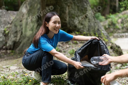 Preview: A young woman collecting trash in nature during an environmental initiative.