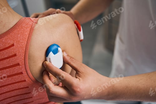 Preview: Close-up massage therapist placing electrostimulator on woman shoulder. Physiotherapy myostimulation