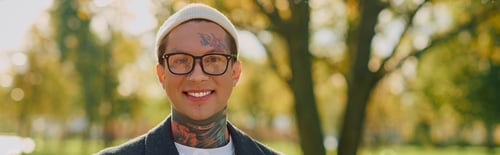 Preview: Stylish young man with tattoos radiates confidence in a sunny park setting