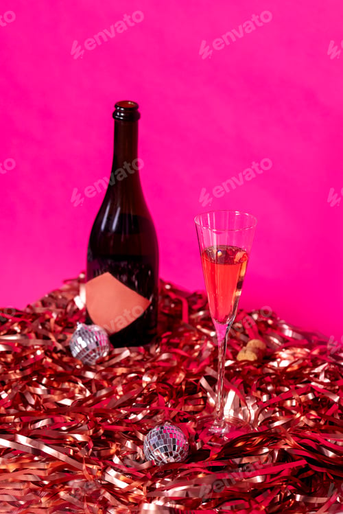 Preview: A bottle of champagne and a glass on shiny pink foil