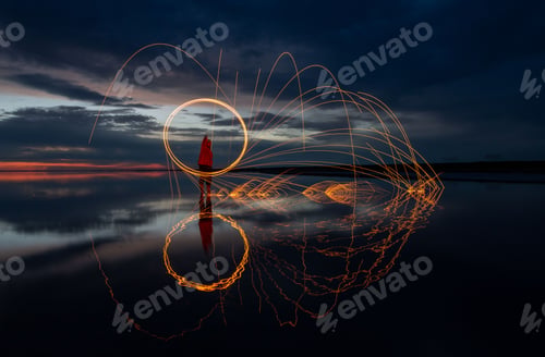 Preview: Beautiful shot of burning steel wool on scenic dark sunset background with a reflection on a lake