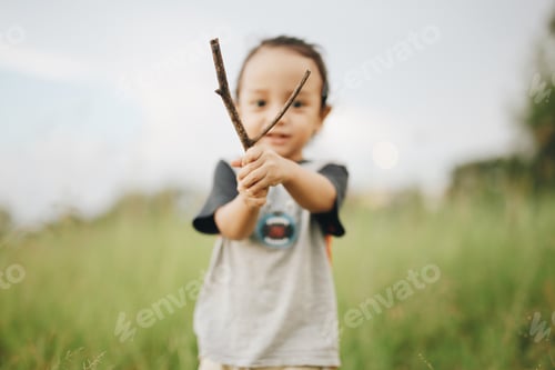 Preview: Child Holding a Stick in a Grassy Field