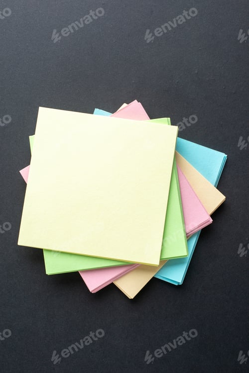 Preview: Above view of stacked sticky coloured note cubes on isolated black wave background with free space