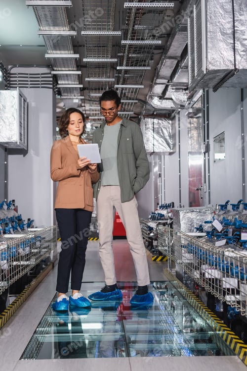 Preview: multiethnic engineers looking at digital tablet near cooling system in data center