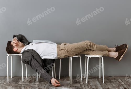 Preview: tired businessman with documents sleeping on chairs wile waiting for job interview