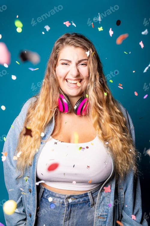 Preview: Caucasian female dancing having fun spreading confetti on blue background