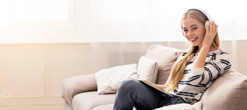 Preview: Woman Smiling, Listening with Headphones on Couch