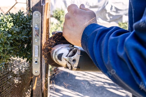 Preview: worker cutting old door lock from iron gate