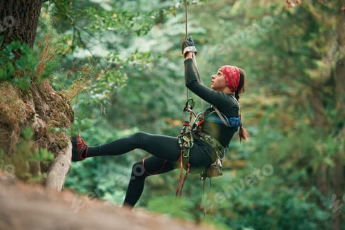 Preview: hanging on the rope. Woman is doing climbing in the forest by the use of safety equipment