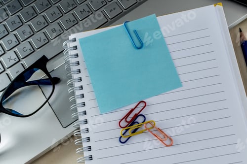 Preview: High angle shot of colorful paper clips on a blank notepad on a laptop