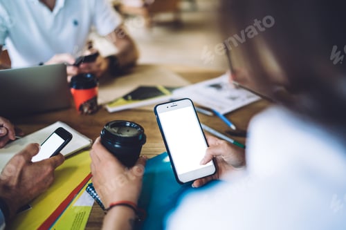 Preview: Crop coworkers using smartphones in cafe