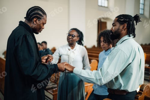 Preview: Priest holding hands with family praying in church