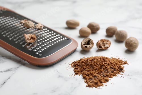 Preview: Grater, nutmeg powder and seeds on white marble table